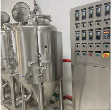 Two large stainless steel fermentation tanks beside a control panel with various buttons.