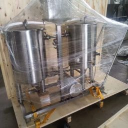Stainless steel CIP skid enclosed in plastic wrap on a wooden pallet.