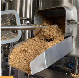Removing grains out of the mash tank in a brewery setting.