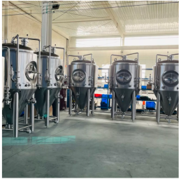 Stainless steel fermentation tanks arranged in a well-lit industrial space.