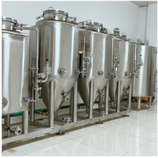 Row of stainless steel fermentation tanks in a clean, industrial workspace.