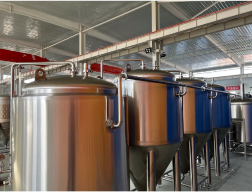 Rows of large stainless steel fermentation tanks in a brewing facility.