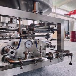 Close-up of stainless steel machinery with valves and gauges in a factory setting.