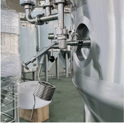 Stainless steel brewing equipment with a pressure gauge and valves.