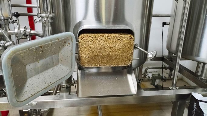 Image of spent grains in the mash tun ready to be removed from the manway door.