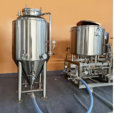 Stainless steel fermentation tanks positioned on a flat surface with hoses attached.