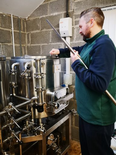 Image of brewer ready to mash in on his brewhouse with a mixing paddle.