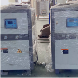 Two wrapped chiller machines with digital displays positioned in a factory or industrial setting.