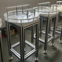 Rotary table stands with circular tops, designed for holding cans, on a workshop floor.
