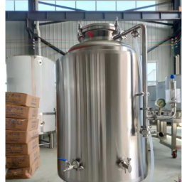 Stainless steel tank with valves, situated in an industrial setting.